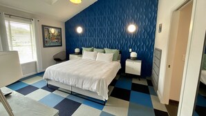 Una camera da letto con un letto grande, una ventola a soffitto, un comodino con una lampada e una luce a parete.