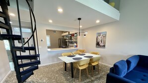 Un interno moderno con zona pranzo, un divano blu e una scala a chiocciola.
