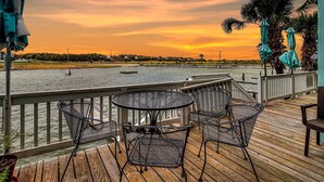 A wooden deck with metal chairs and tables overlooking a body of water at sunset. - Carols Coastal K502 3 Bedroom Condo by RedAwning (Rockport)