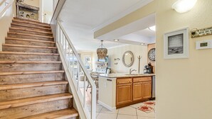 A wooden staircase leading to a kitchen with a view of the outdoors. - Carols Coastal K502 3 Bedroom Condo by RedAwning (Rockport)