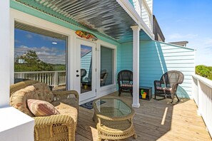 A covered outdoor deck with wicker furniture, a glass table, and a door leading to a covered area. - Mom's Gift / 256-b Brunswick Ave West 2 Bedroom Home by RedAwning (Supply)