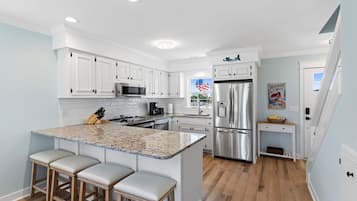 A modern kitchen with white cabinets, a stainless steel refrigerator, and a granite countertop.