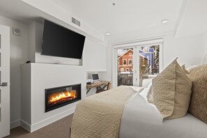 Une chambre moderne équipée d’une cheminée, d’un téléviseur à écran plat et d’un bureau avec un ordinateur portable.