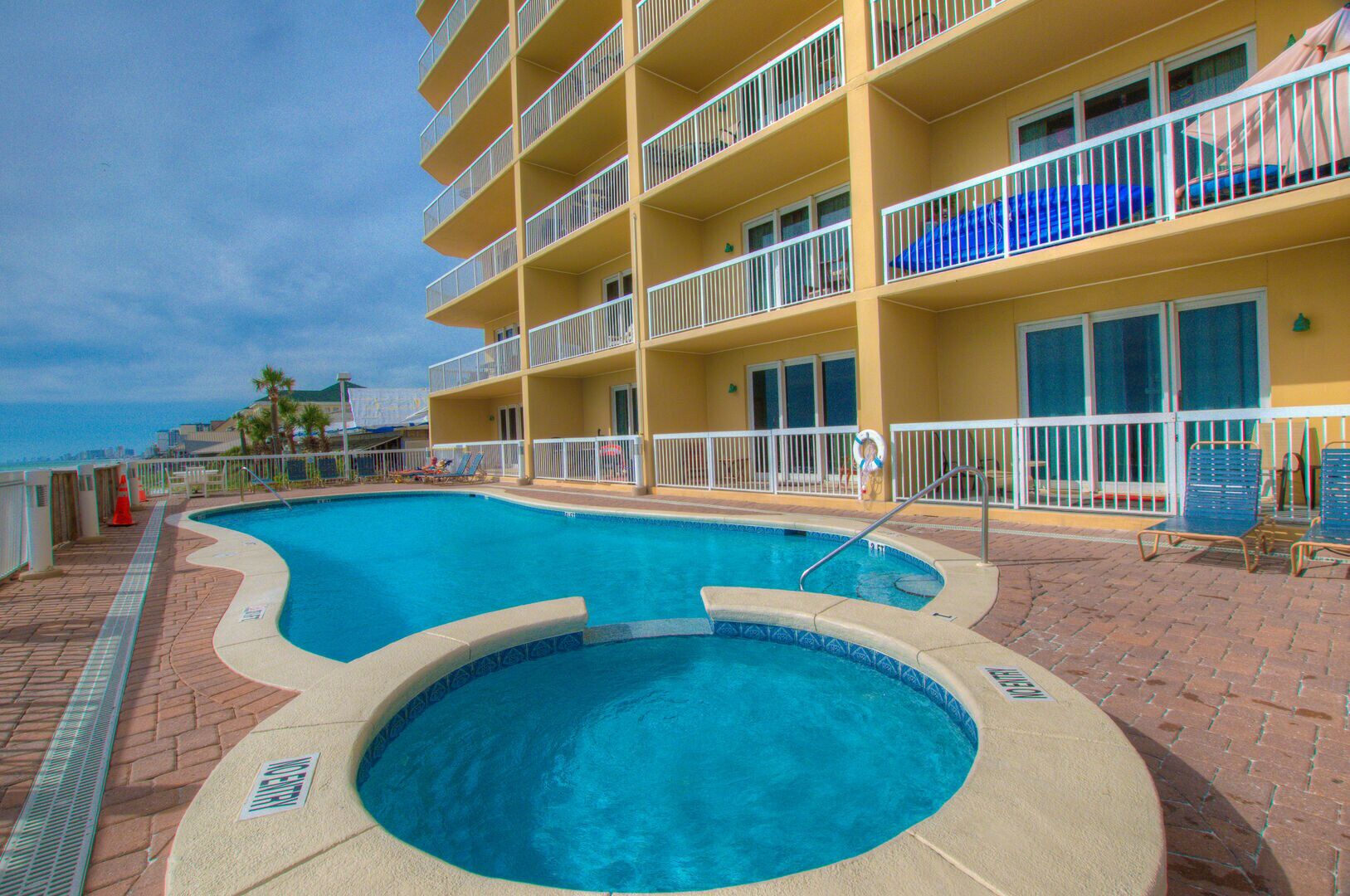 A hotel with a large pool, multiple balconies, and a view of the ocean.