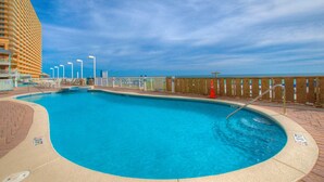Una piscina amplia y clara con cubierta de madera y vista a un edificio alto al fondo.