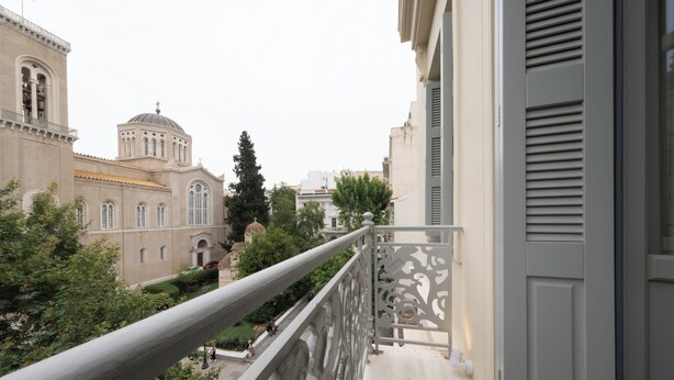 Un balcón con vista a un edificio histórico con una cúpula y ventanas de arco.