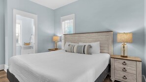 A bedroom with a large bed, two bedside tables with lamps, a wooden headboard, and a white nightstand. - Dog Friendly @ Bungalows at Seagrove; 2 Blocks to Beach ~ Overlooks Pool/spa (Santa Rosa Beach)