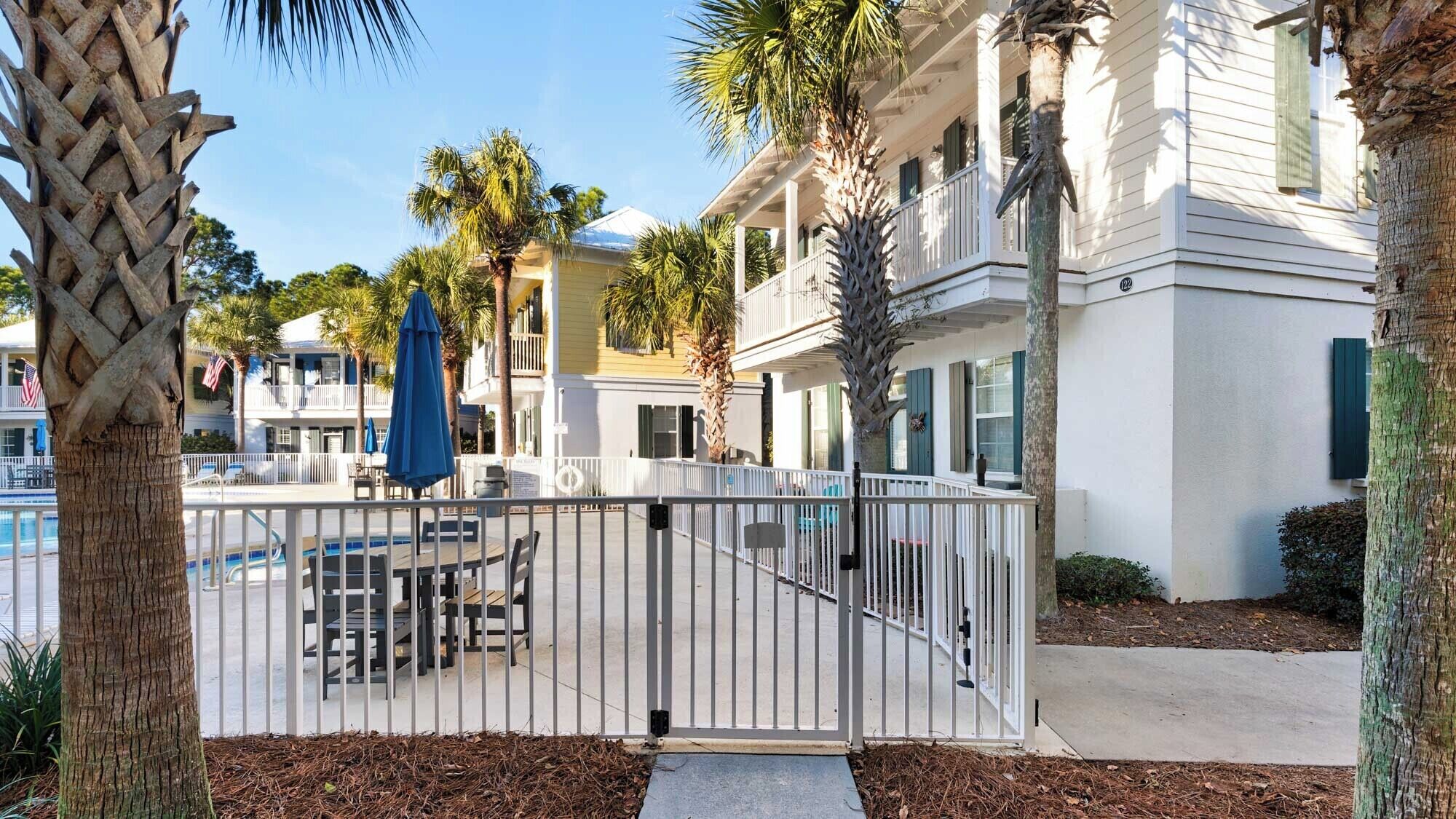 A gated pool area with outdoor seating and palm trees.
