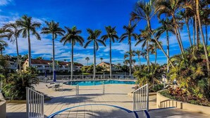 A swimming pool surrounded by palm trees and a clear blue sky.