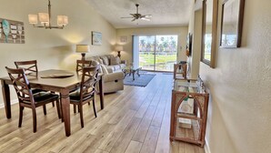 A spacious living area with a dining table, chairs, a sofa, and a ceiling fan.
