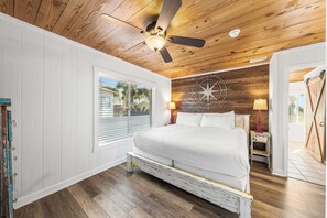 Un dormitorio con techo de madera, una cama, una ventana y un adorno de brújula en la pared.