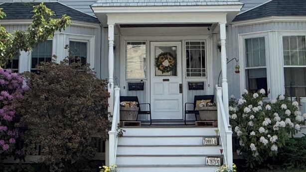 Une maison à deux étages avec un porche à l’avant, une boîte aux lettres et une porte d’entrée.
