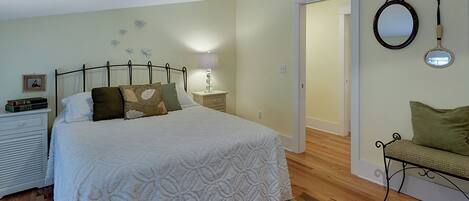 Un dormitorio con cama, mesita de noche, lámpara y un espejo en la pared.