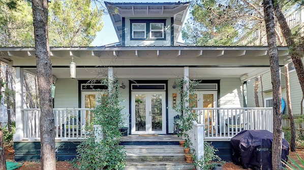 A two-story house with a porch, a covered front door, and a small upper deck.