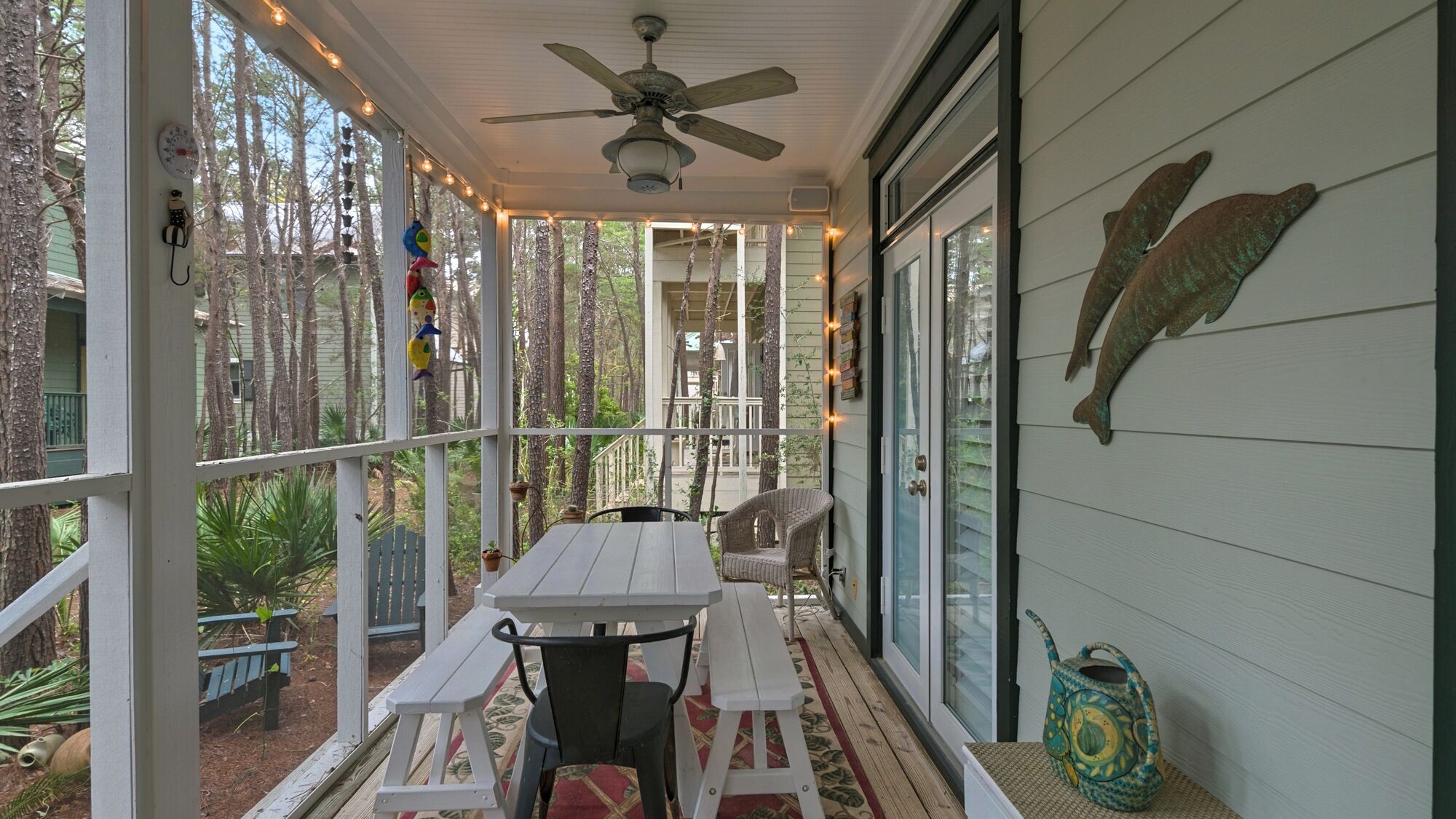 A covered porch with a ceiling fan, wooden benches, and a table.