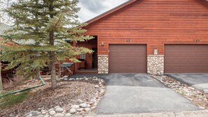 A two-story log cabin with a stone foundation, numbered garage doors, and a well-maintained driveway. - Cozy Mountain Retreat (Dillon)
