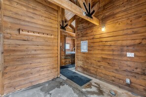 A wooden cabin interior with a spa rules sign, a metal door frame, and a concrete floor. - Cozy Mountain Retreat (Dillon)