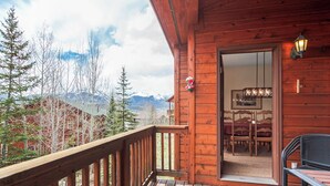 A wooden cabin with a deck, a dining area with a table and chairs, and a view of mountains. - Cozy Mountain Retreat (Dillon)