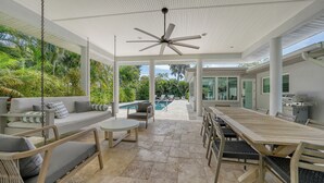 Eine überdachte Terrasse im Freien mit Pool, Sitzgelegenheiten und Grillbereich.