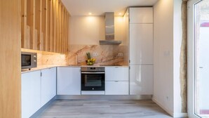 Een moderne keuken met witte kasten, een ingebouwde oven en een wand met houten accenten.