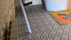 Un baño con bañera, baldosas de suelo estampadas, alfombra de cebra y puerta de madera.