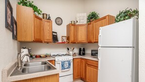 A kitchen with wooden cabinets, a white refrigerator, a stove, a sink, and various kitchen items. - Wide open spaces getaway (Concho)