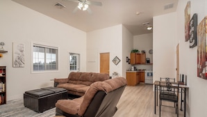 A living room with a sectional sofa, a small table, and a dining area with chairs. - Wide open spaces getaway (Concho)