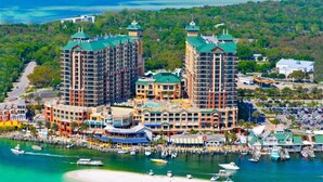 Ein Küstenhotel mit mehreren Hochhäusern, einer Marina voller Boote und einem Strand.