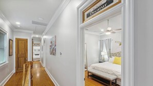 Ein Hotelgang mit einer hölzernen Bank, einem Bett mit weißer Bettdecke und einem Schild mit der Aufschrift 'Rue Decatur'.