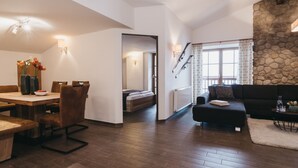 Un salon moderne avec un plancher en bois, un coin repas comprenant une table et des chaises, un canapé et un escalier menant à un niveau supérieur.
