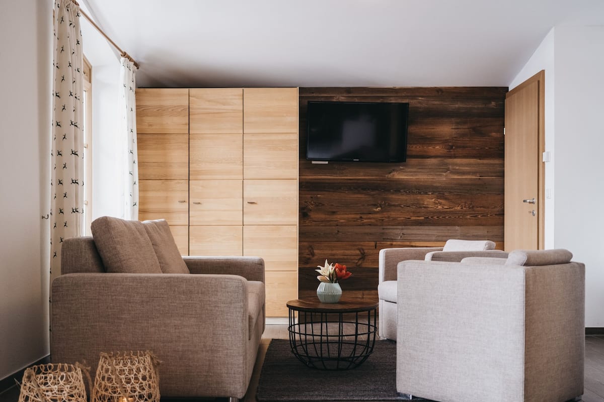 Un salon moderne avec deux canapés, une table basse et un téléviseur fixé à un mur en bois.