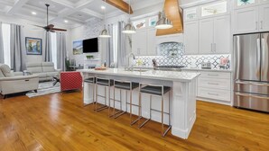 Una cocina moderna con armarios blancos, electrodomésticos de acero inoxidable y una isla central con taburetes de bar.