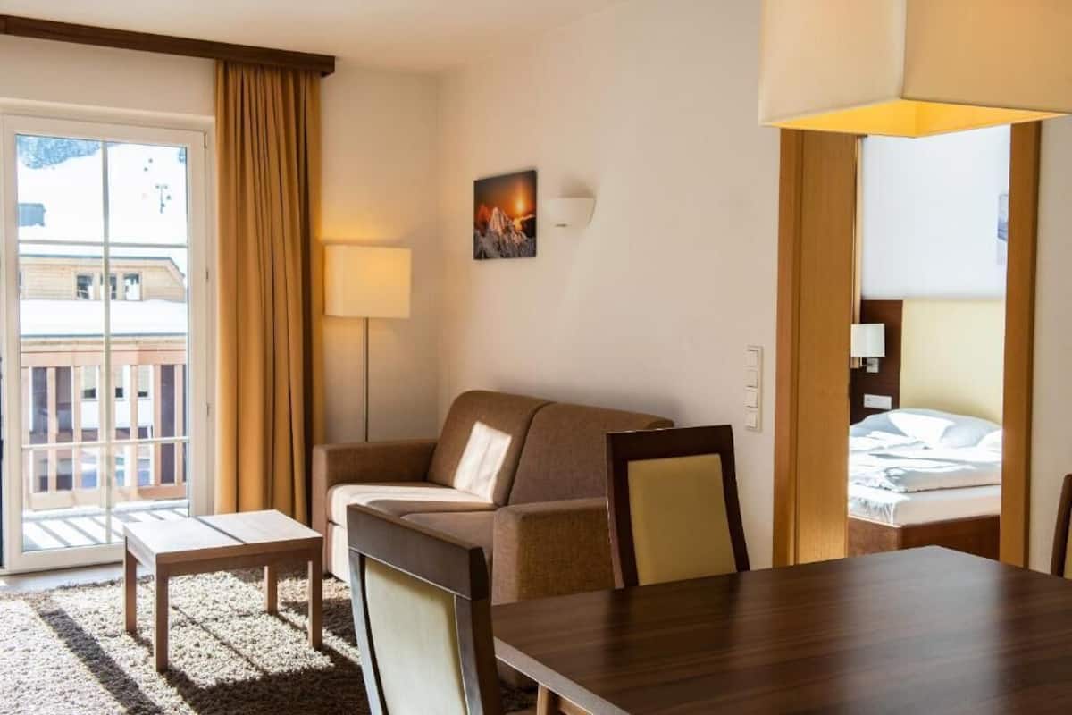Une chambre d’hôtel avec un canapé, une petite table, un lit et une vue sur l’extérieur.