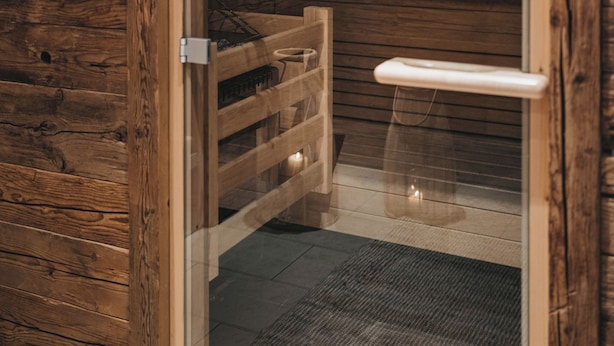 Une entrée en bois menant à un sauna, avec un panneau indiquant une température comprise entre 60 et 65 °C.
