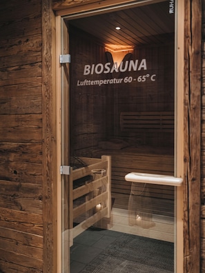 A wooden sauna entrance with a sign indicating a temperature range of 60 - 65°C. - Residence Saalbach (Saalbach-Hinterglemm)
