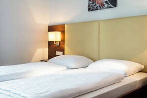 Ein Hotelzimmer mit einem Bett, einem Nachttisch und einer Wandlampe.