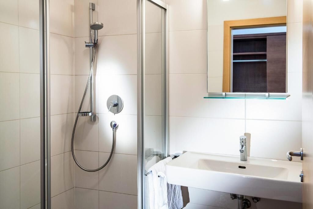 Une salle de bain moderne avec une douche à parois de verre, un lavabo blanc et un miroir avec un cadre en bois.