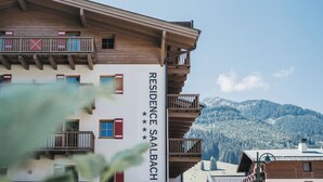 Un immeuble à plusieurs étages, doté d’une façade en bois, de balcons et d’une enseigne indiquant « RÉSIDENCE SAALBACH ».