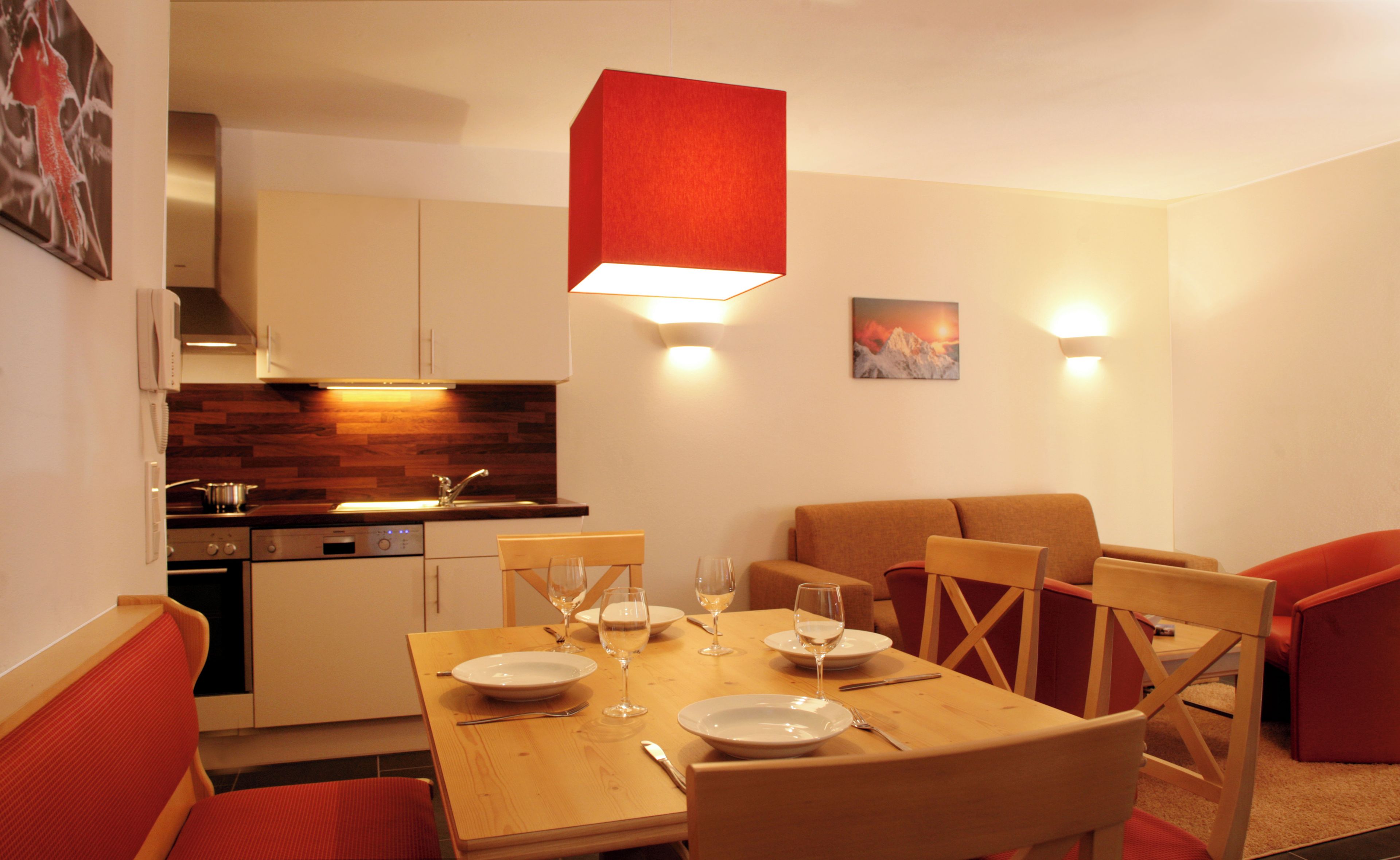 Une cuisine moderne avec un coin repas, comprenant une table dressée pour deux personnes, avec des verres à vin et des assiettes.