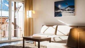 Un salon moderne avec un canapé, une table basse et une grande fenêtre donnant sur une montagne enneigée.