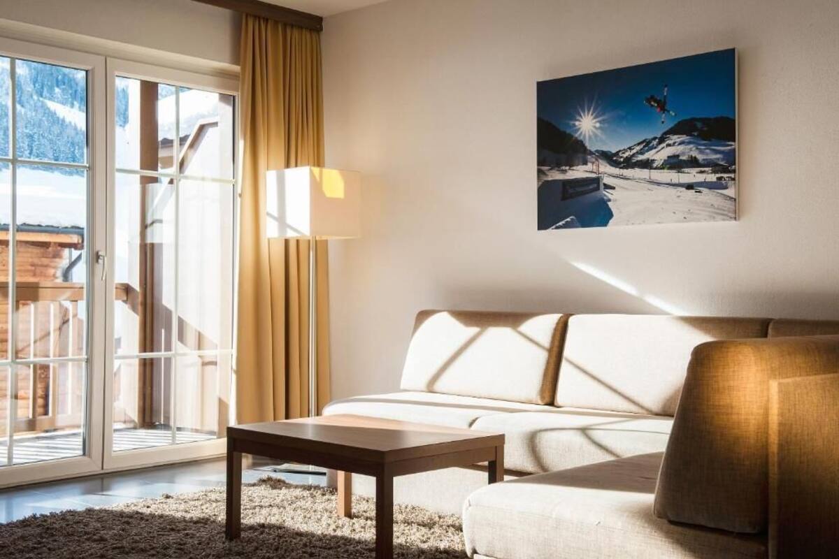 Un salon moderne avec un canapé, une table basse et une grande fenêtre donnant sur une montagne enneigée.