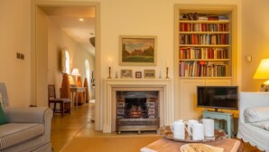 Un salon chaleureux avec une cheminée, une bibliothèque et un téléviseur.