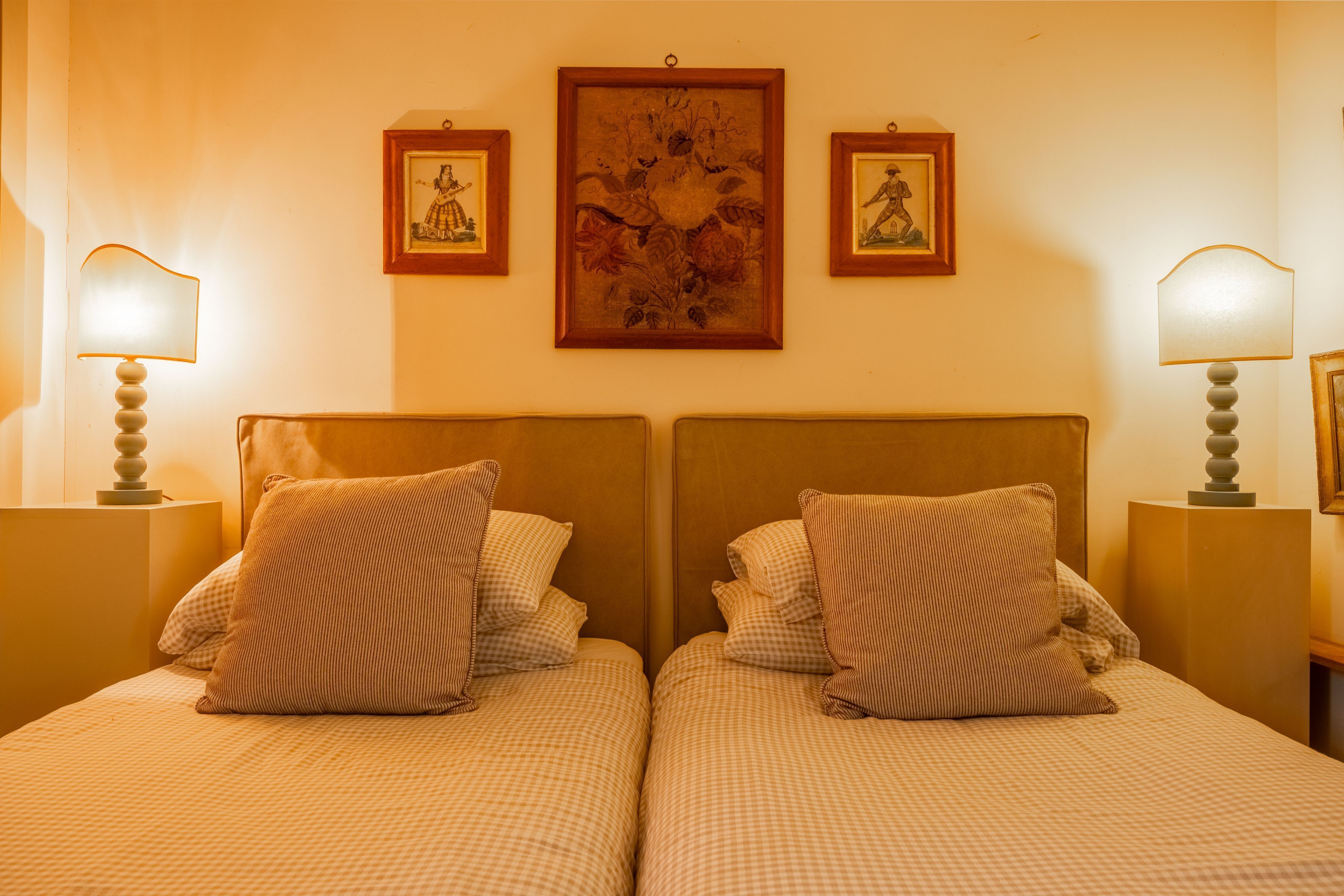 A double bed with a checkered bedspread and two pillows, flanked by nightstands with lamps.