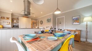 A modern kitchen with white cabinets, a wooden island, and colorful chairs. - Spring Cottage, Burnham Market, Norfolk (Wells-next-the-Sea)