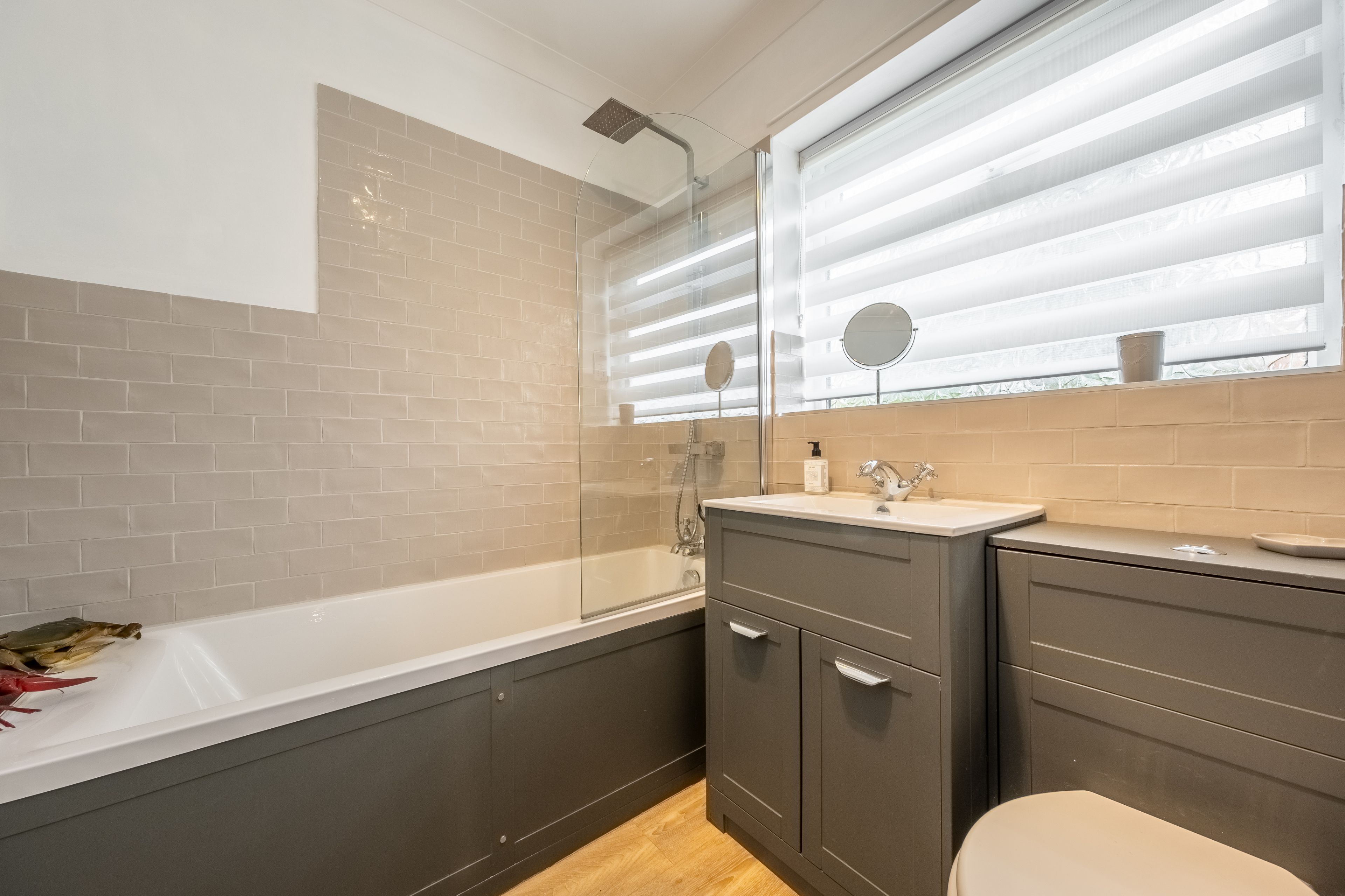 A modern bathroom with a bathtub, a shower, a vanity with a sink, and a toilet.