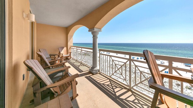 Ein Balkon mit Holzstühlen und Blick auf den Strand.