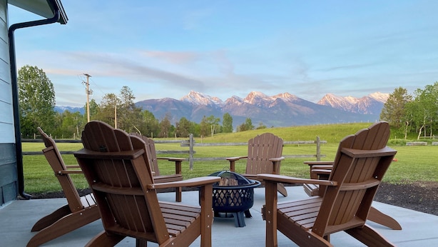 A patio with Adirondack chairs and a fire pit, overlooking a mountain range. - River House to Relax, Rejuvenate, and connect with the quietness of nature. (Saint Ignatius)