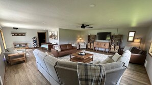 A spacious living room with a large sectional sofa, a coffee table, and a television. - River House to Relax, Rejuvenate, and connect with the quietness of nature. (Saint Ignatius)