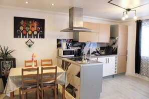 Una cocina compacta con microondas, estufa y muebles de cocina modernos. Hay una zona de comedor con mesa y sillas.