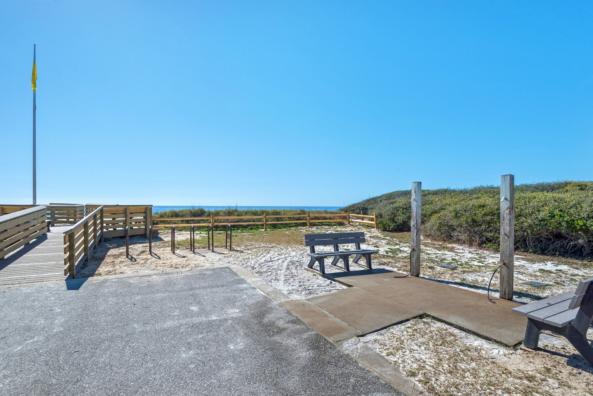 Une promenade en bord de mer avec des garde-corps en bois, un chemin en béton et une table de pique-nique.